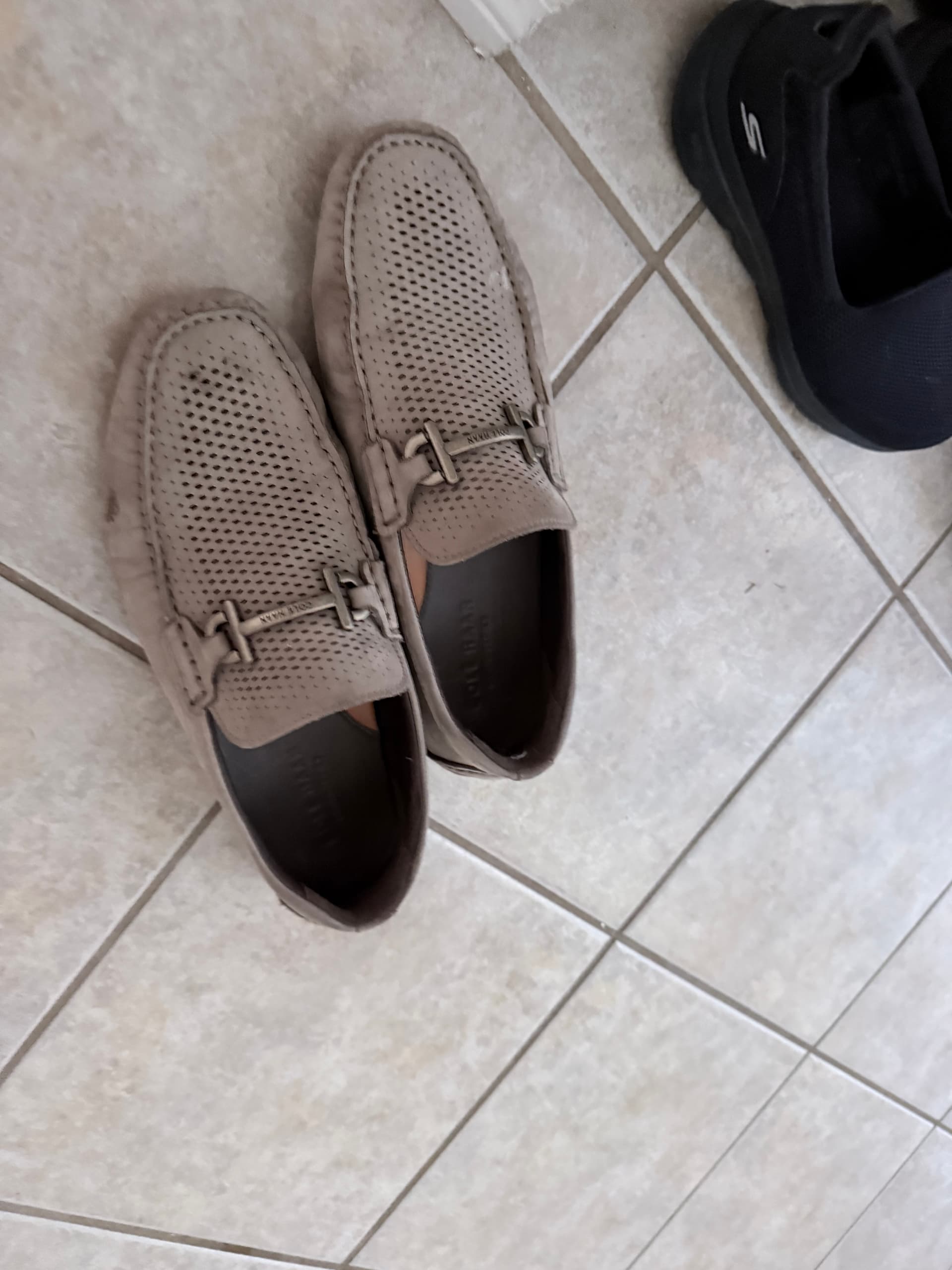 Perforated grey loafers on a tiled floor