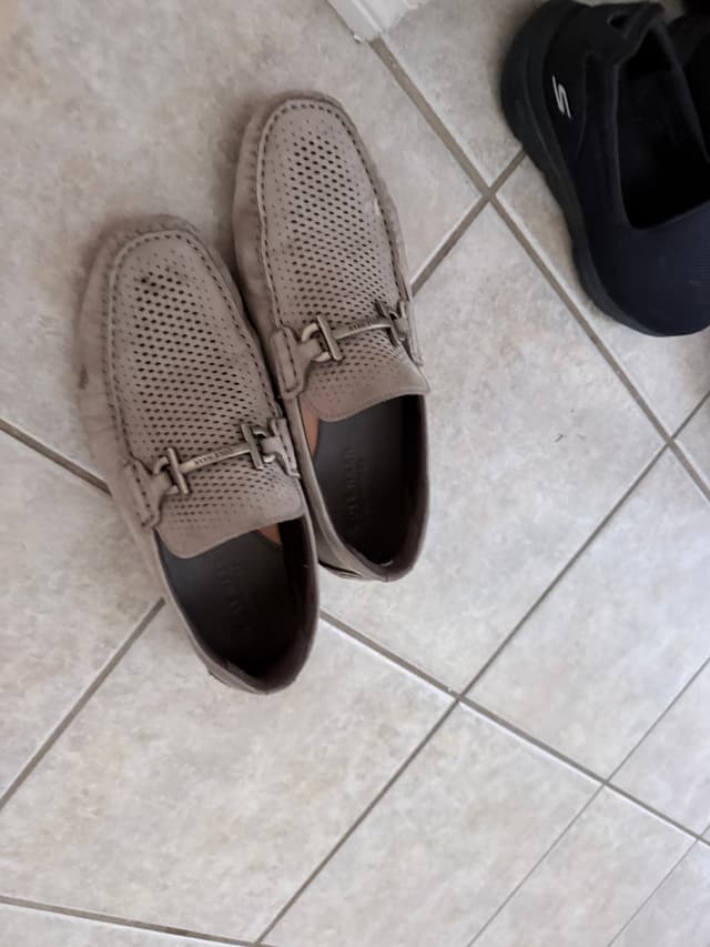 Perforated grey loafers on a tiled floor